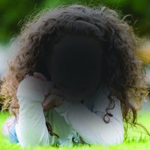 image of a girl with curly hair with blind spot over her face simulating AMD
