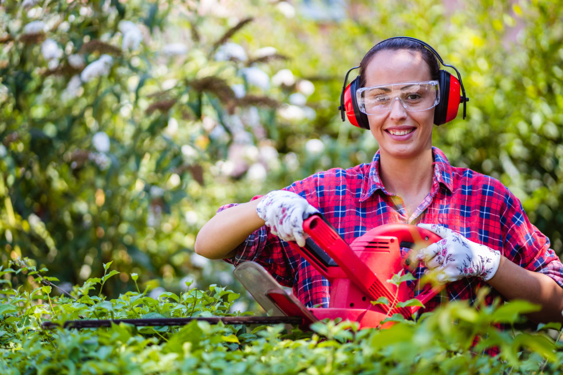 woman using hedge trimmers with safety glasses