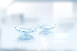 A pair of fresh contact lenses on a clean reflective surface.